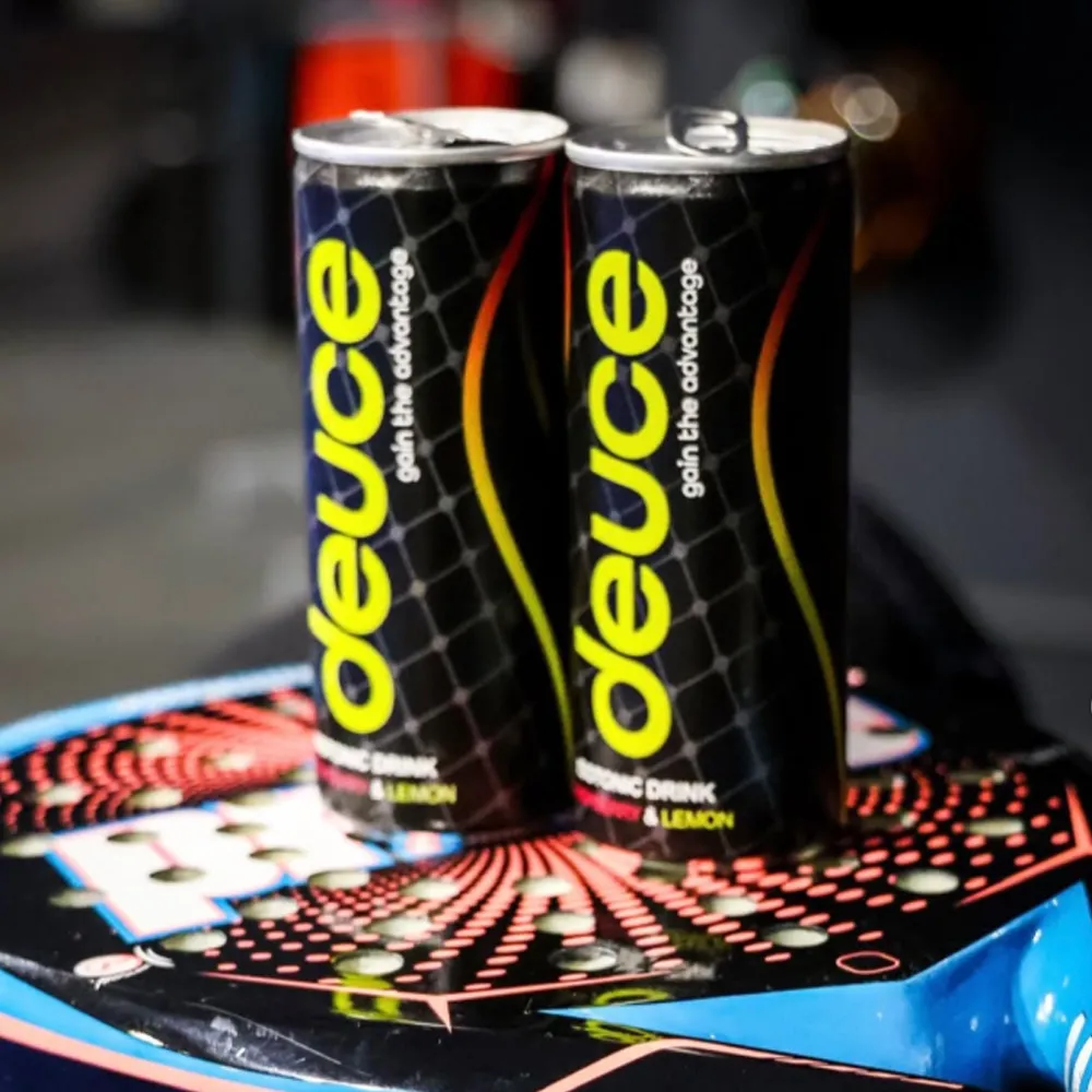 Two cans of Deuce energy drink, featuring a black design with bright yellow lettering, placed on a colourful patterned surface.